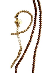 Sautoir petites perles bronze et dorées croix plate style baroque avec une pierre blanche transparente.